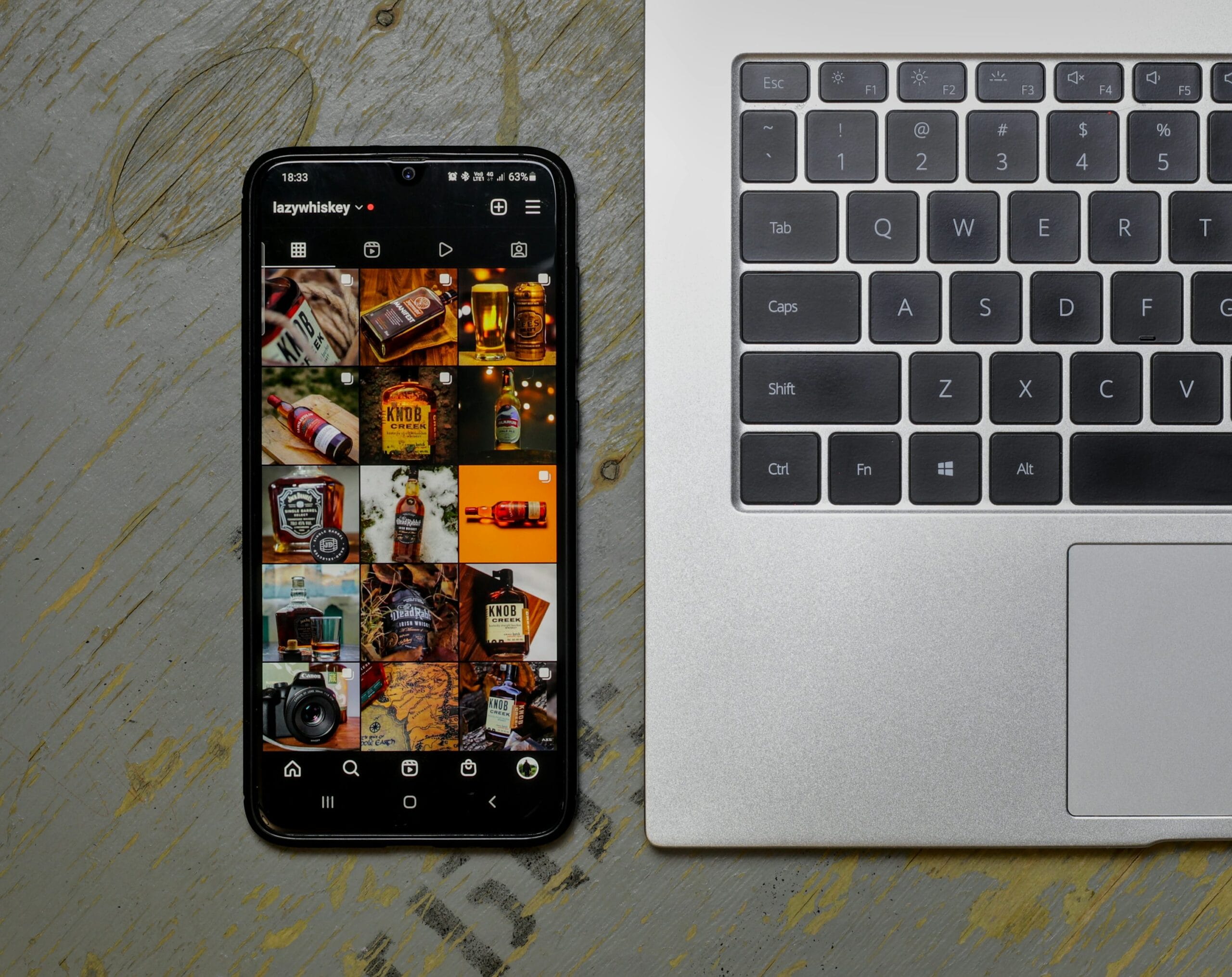 Open laptop next to a smartphone with social media apps — AI meme creation workflow